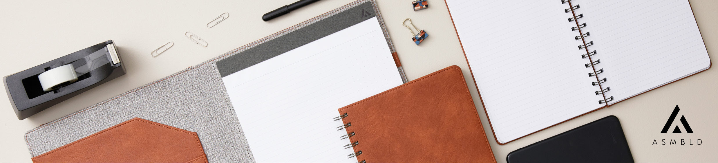 An array of ASMBLD notebooks, leather-bound planners and office supplies