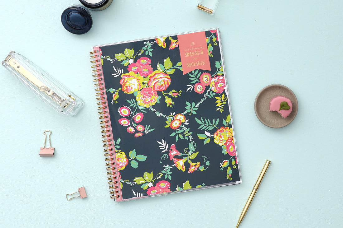 weekly monthly academic planner from Day Designer for Blue Sky featuring a navy background and floral front cover 8.5x11, lifestyle photo on a mint background with pen, macoroon, stapler, and paperclip on the side. 2024-2025 academic year