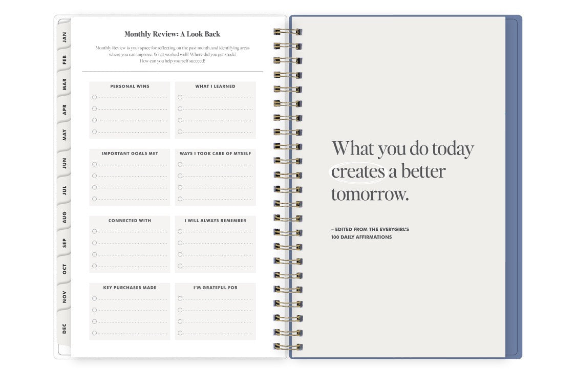 Open planner with monthly review section and motivational quote on a white background