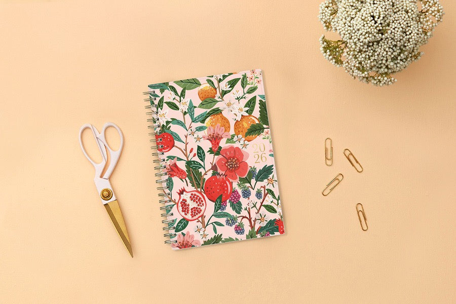 Spiral-bound 2026 planner with floral and fruit design on a pink background