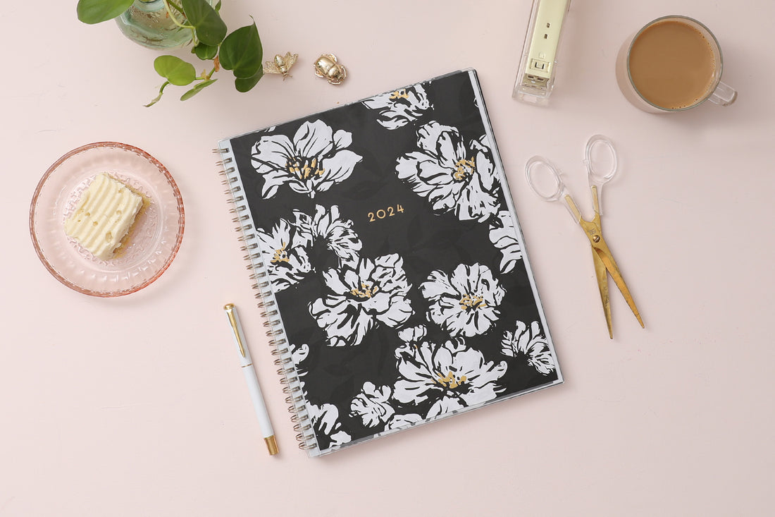 8.5x11 weekly monthly planner for January 2024 - December 2024 new year featuring silver twin wire-o binding, black/gray background, white florals and gold accents