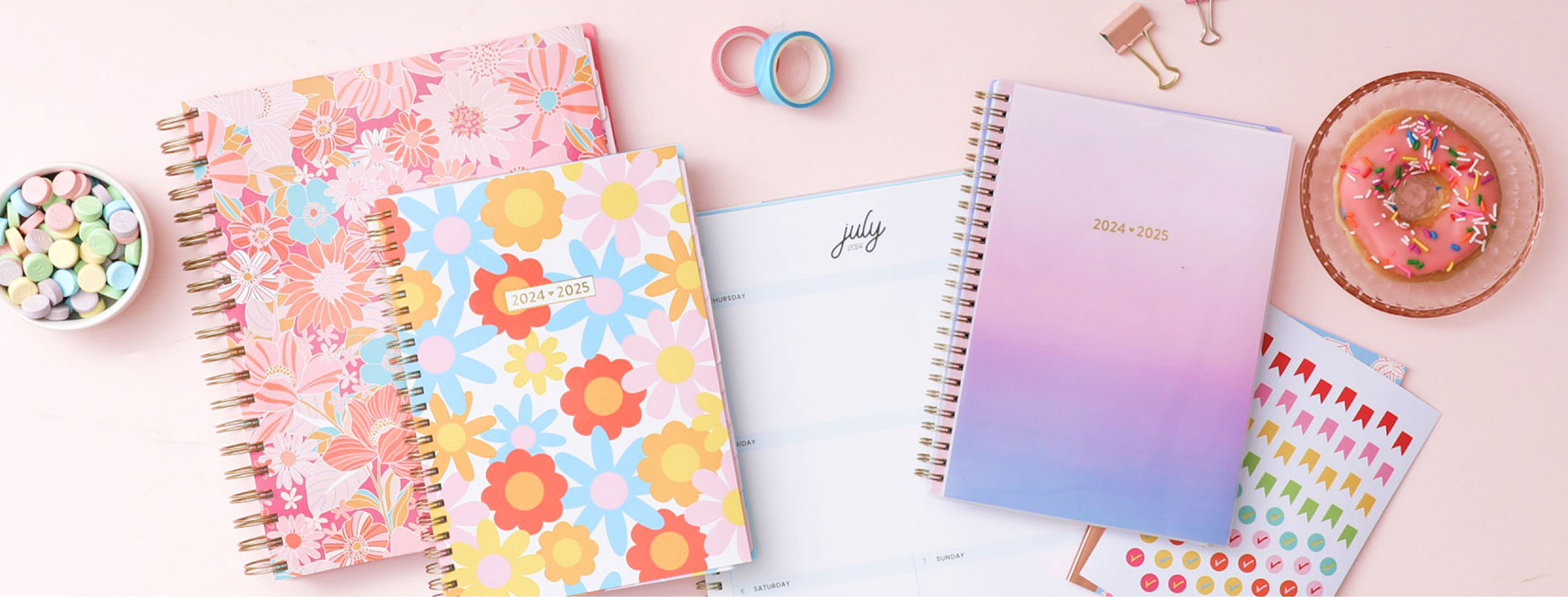 Brighten up your day with various 2024-2025 colorful and vibrant planners, surrounded by a bowl of candies, a plate of donuts and stickers. 