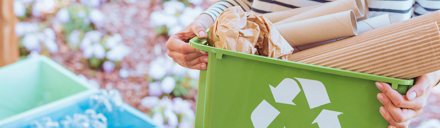 Individual with recycling bin full of paper and cardboard.