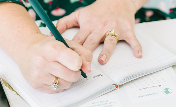 A woman writing in a lined notebook or planner