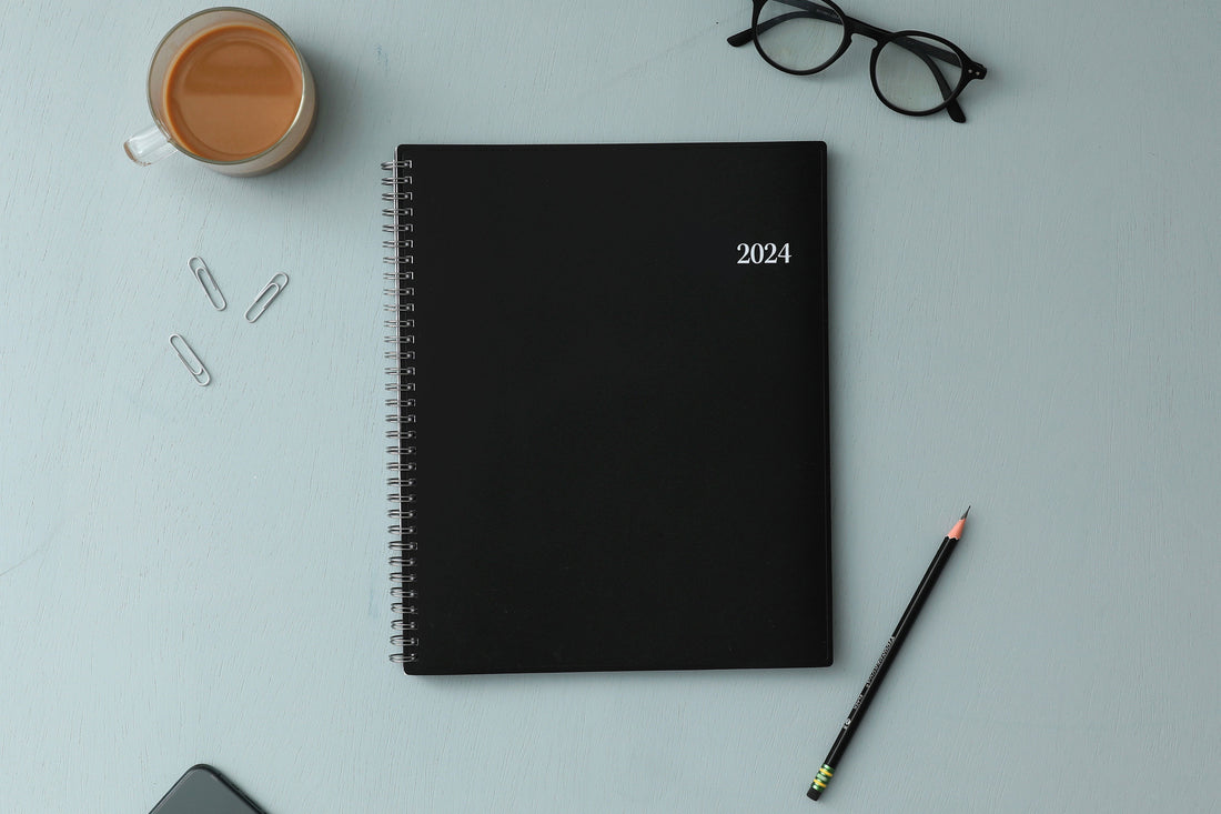 Bilingual January 2024 - December 2024 weekly monthly planner featuring a charcoal front cover design and silver twin wire-o binding 8.5x11 size Calendario De Planificacion.