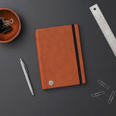 Brown notebook with a black elastic strap on a white background