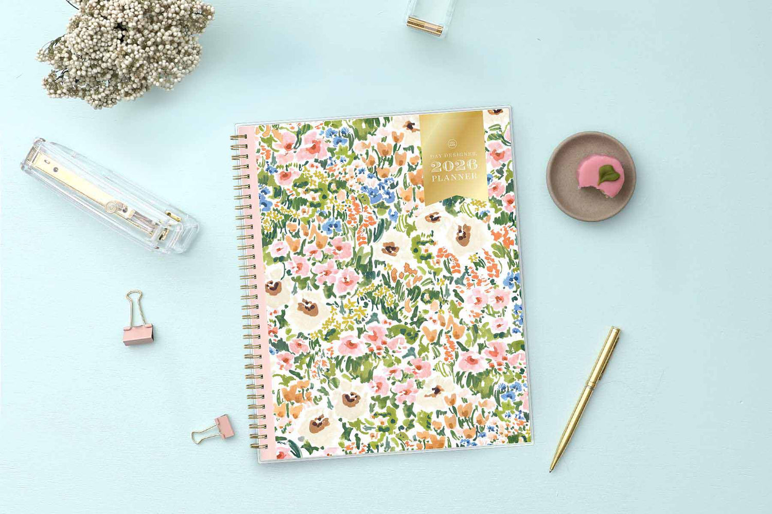 Floral notebook on a light blue surface with stationery items
