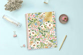 Floral notebook on a light blue surface with stationery items