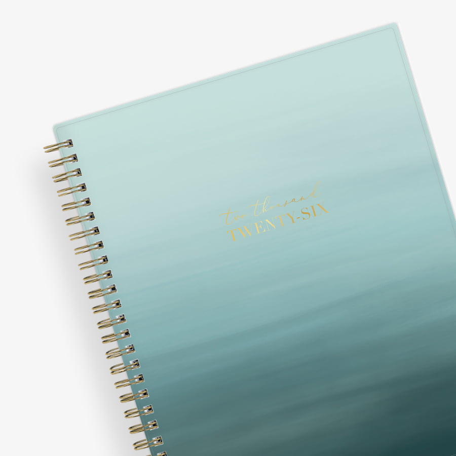 Light blue ocean ombre spiral-bound notebook with gold text on a white background