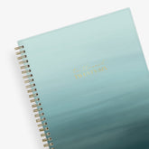 Light blue ocean ombre spiral-bound notebook with gold text on a white background