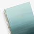 Light blue ocean ombre spiral-bound notebook with gold text on a white background