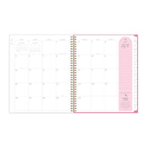 Open planner showing a monthly calendar layout with a pink section for note taking on a white background