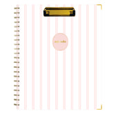 A spiral-bound non-dated planner with a white cover featuring vertical light pink stripes, a gold clip at the top, and a pink oval label in the center with the word &