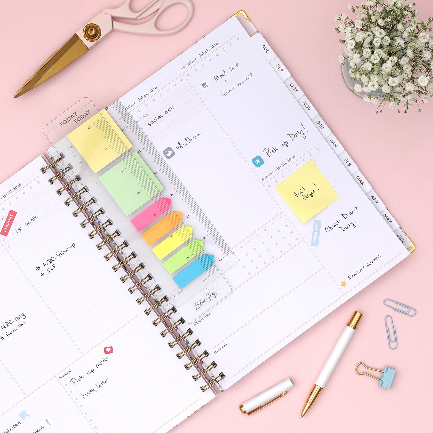 Planner with colorful sticky notes and stationery items on a pink background