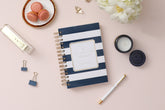 2024 daily monthly from day designer for blue sky featuring a hardcover, navy blue and white stripe design, gold twin wire-o binding in a compact 5x8 planner size.
