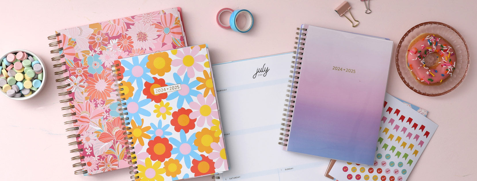 Brighten up your day with various 2024-2025 colorful and vibrant planners, surrounded by a bowl of candies, a plate of donuts and stickers. 
