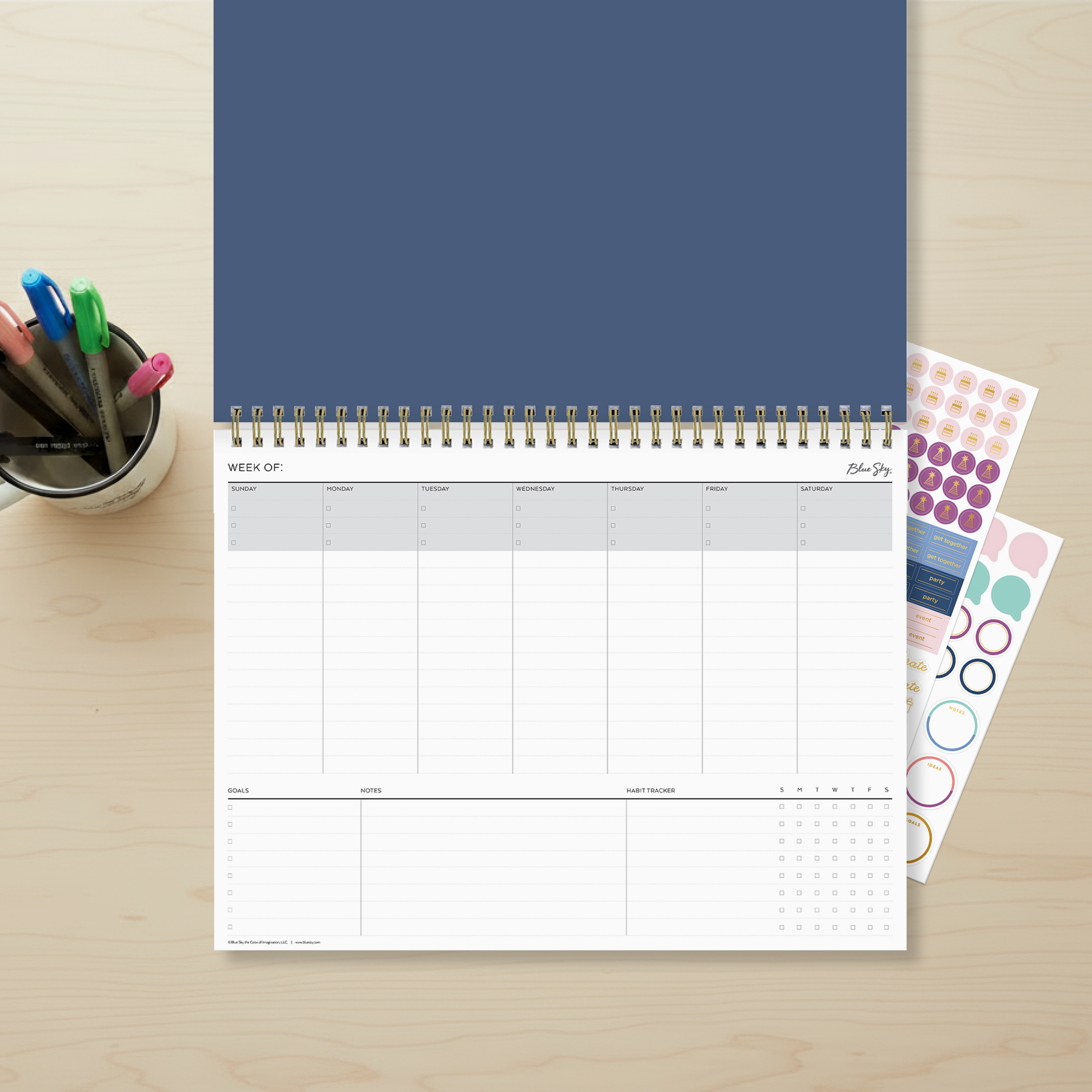 12 x 9 weekly planning pad featuring a navy front cover with twin wire-o, interior layout featuring weekly view Sunday - Saturday with bullet points, lined writing space, goals, notes section, and habit tracker