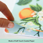 Hand holding a sheet of paper with a floral design, labeled &