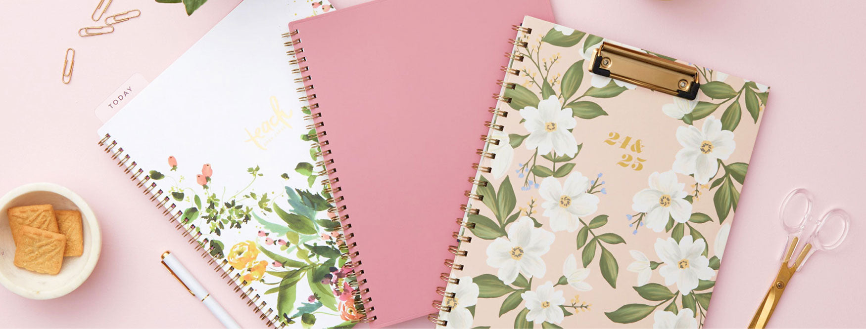 A pink planner and two planners adorned with flowers and a pen to the left. A perfect combination for jotting down your lesson plans, schedules and ideas.