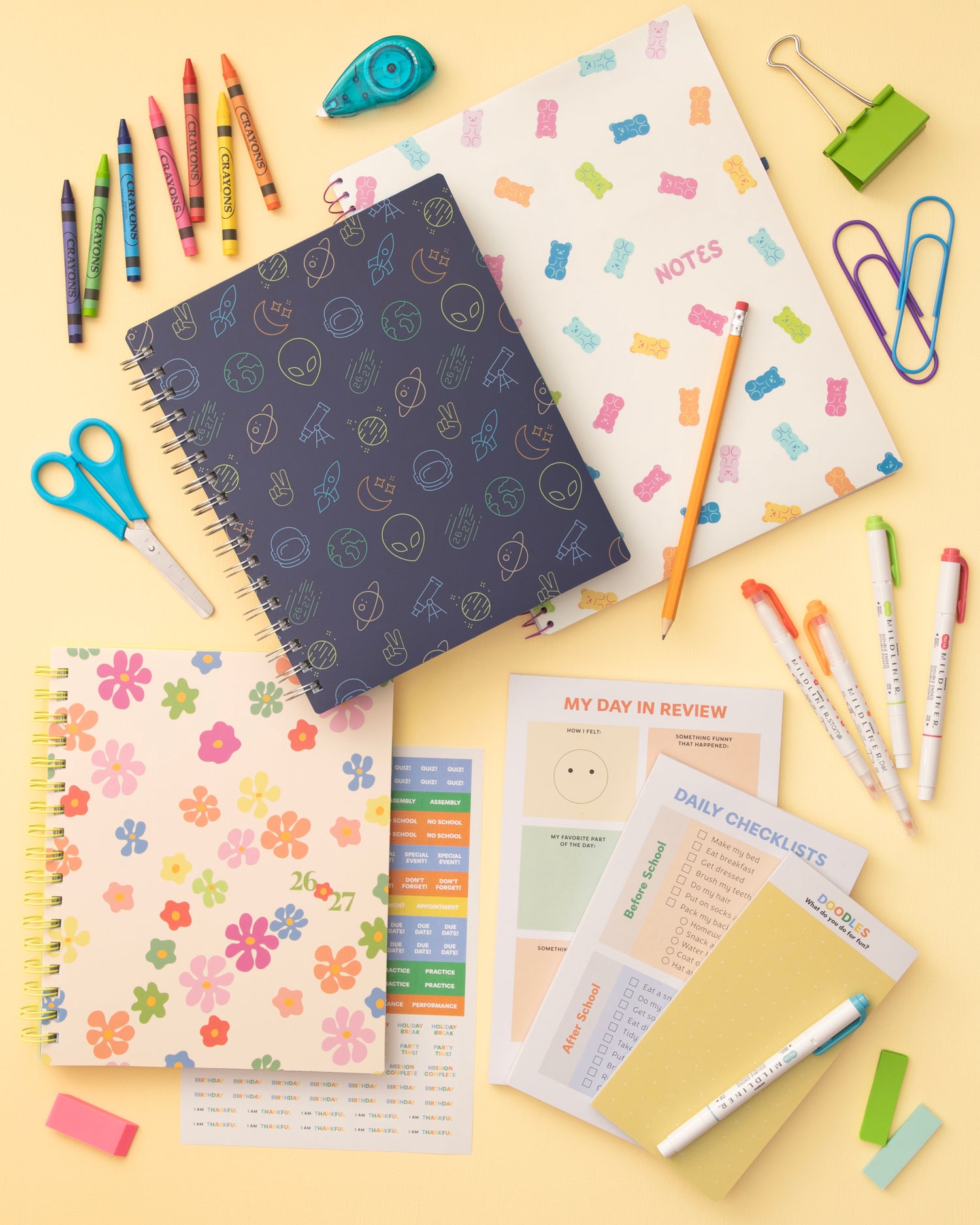 Assorted stationery items including notebooks, pens, and office supplies on a yellow background
