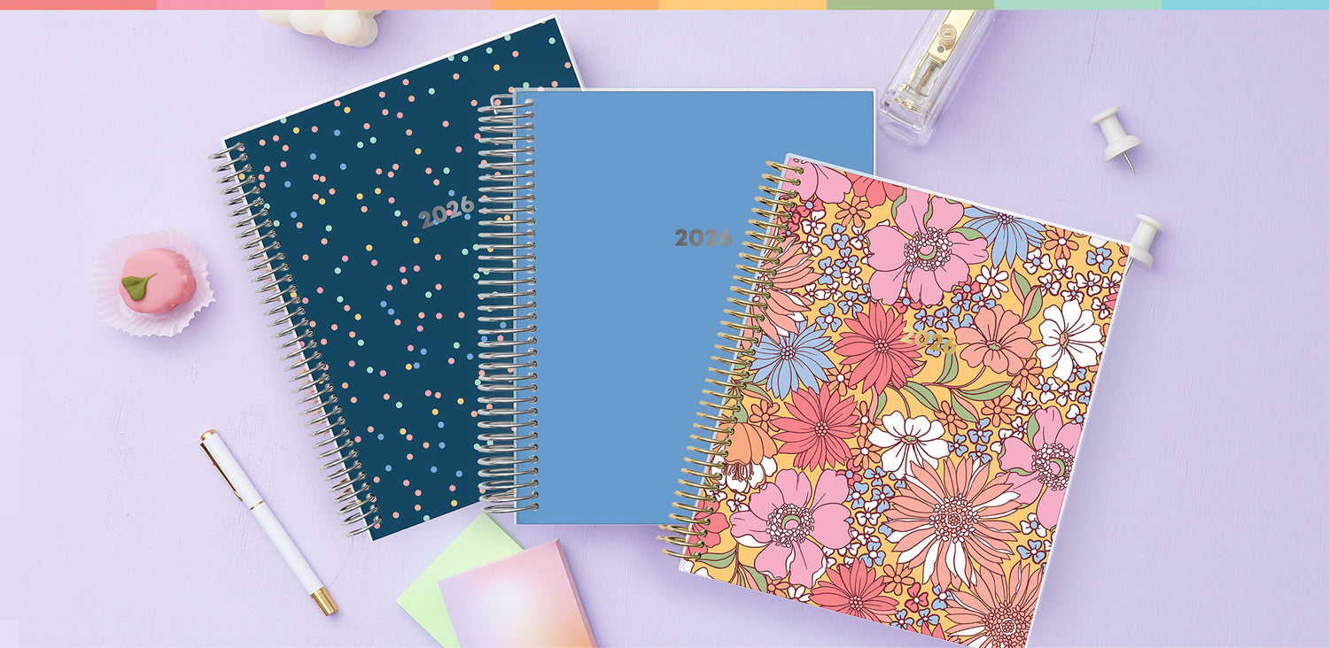 Three spiral-bound LiveWell planners on a light purple background with stationery items.
