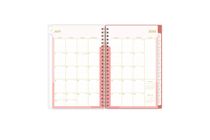 This 2023-2024 weekly monthly planner features a monthly spread with lined writing space, notes section, reference calendars and white monthly tabs with gold imprints