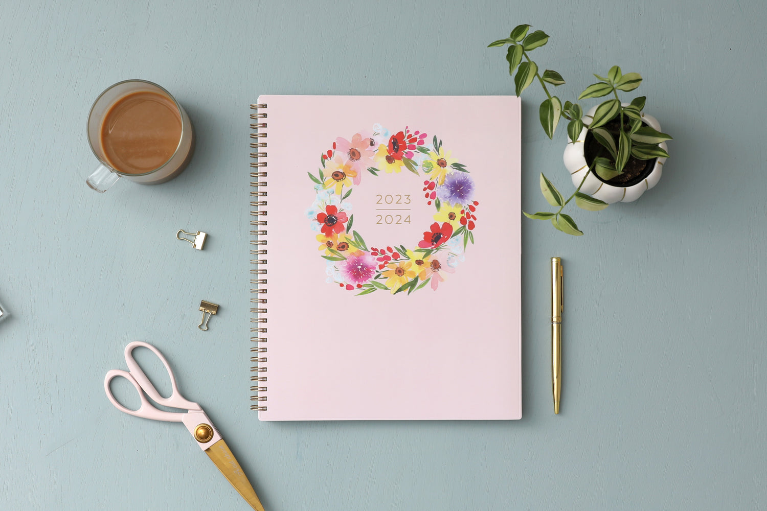Bright colored floral wreath with 2023-2024 academic year planner on soft coral background gold wire binding 8.5x11 size